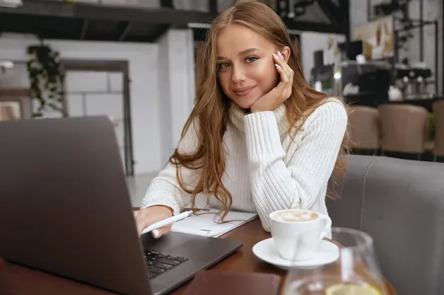 A freelancer at a sunny desk generating an invoice on a laptop