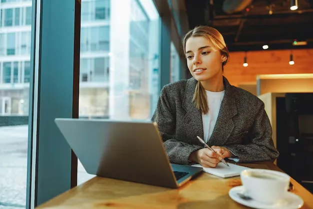 A small business owner reviewing payment reminders on a laptop with a coffee